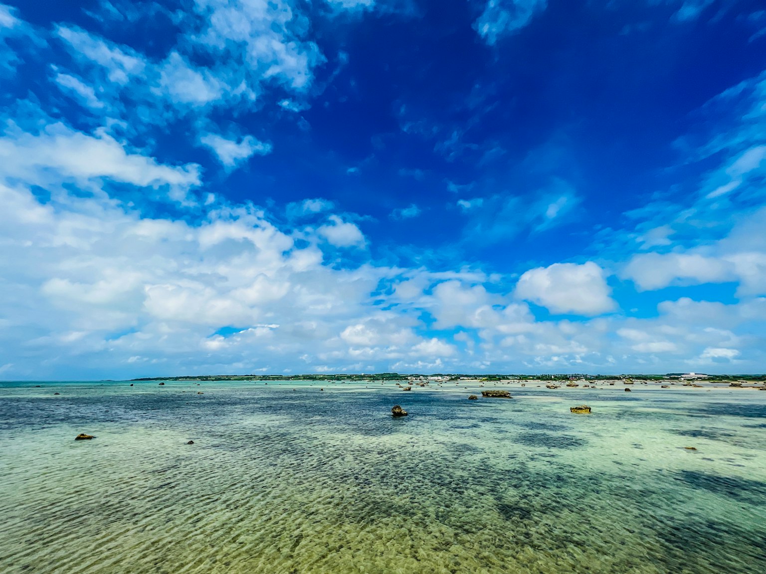 Amplio cielo azul con nubes blancas sobre un océano sereno