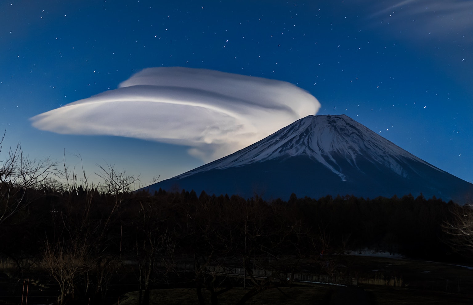 Mount Fuji with a unique lenticular cloud in a starry night sky