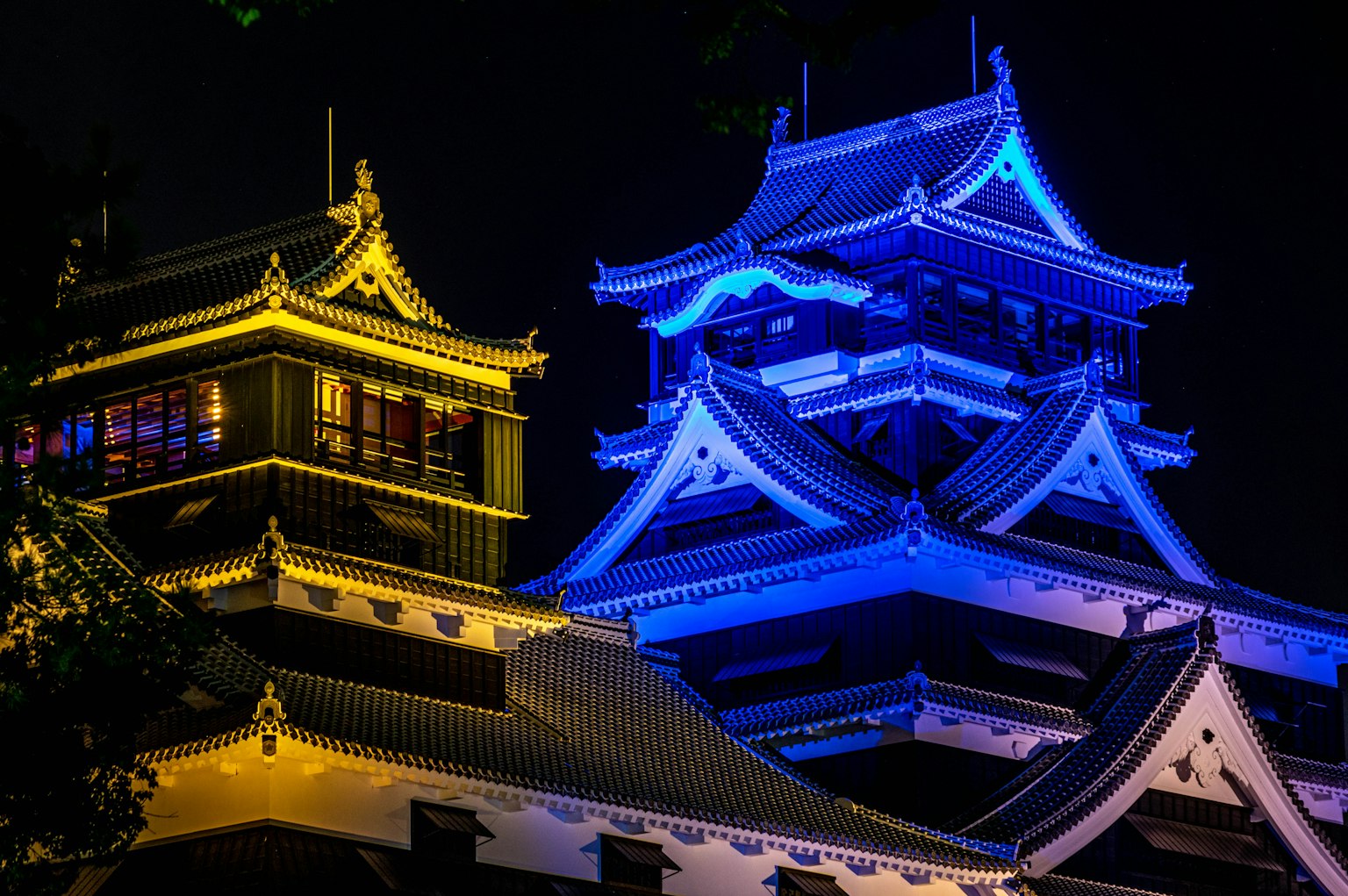 หอคอยปราสาทที่สวยงามสว่างไสวในยามค่ำคืนด้วยแสงสีฟ้าและทอง