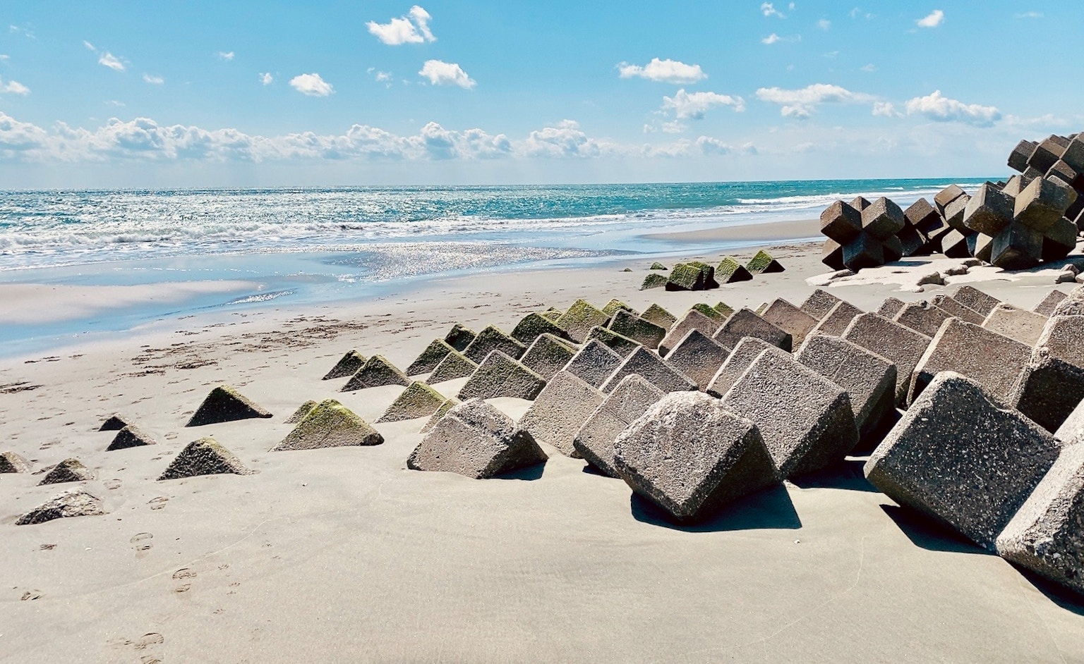 Blocs en béton disposés sur une plage de sable avec un ciel bleu