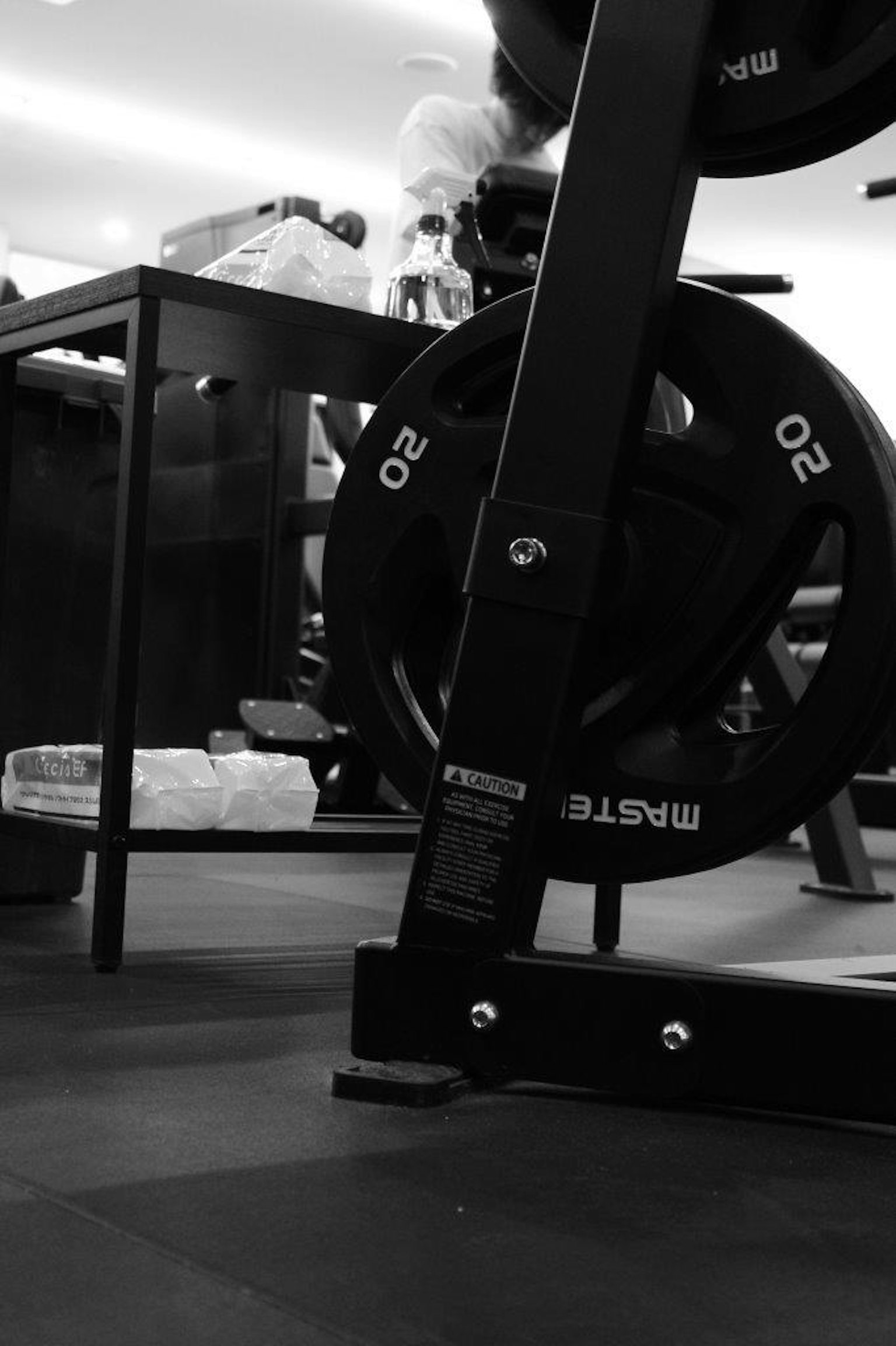 Black and white image of gym equipment with weights and a training bench