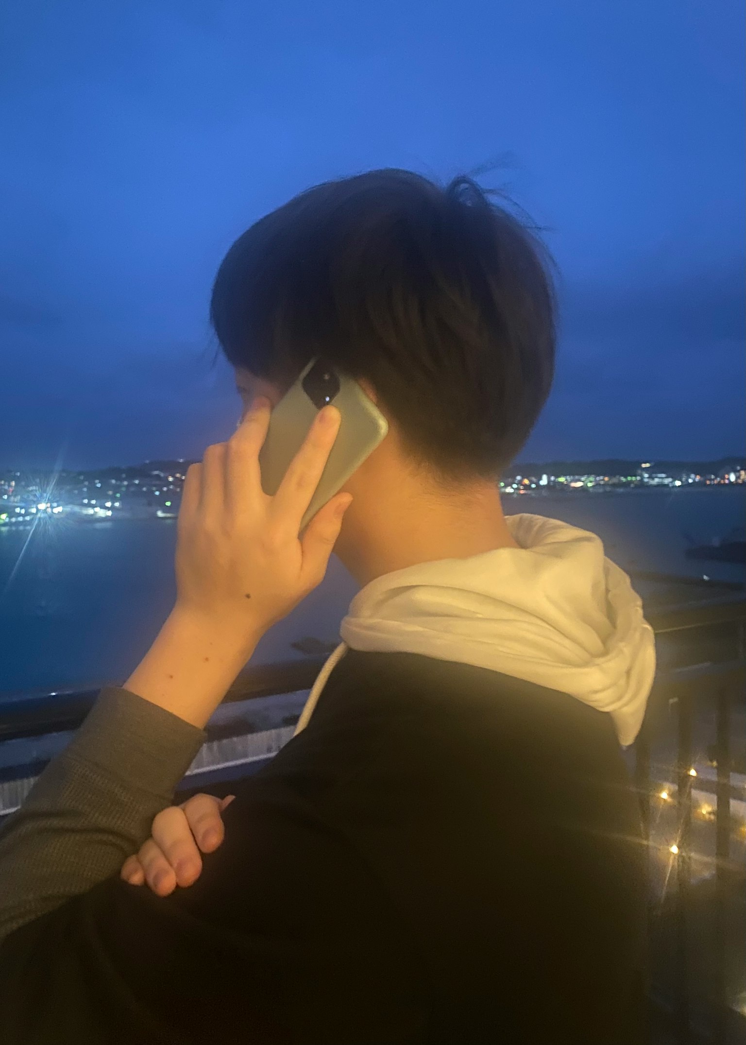 Persona hablando por teléfono con un horizonte urbano de noche