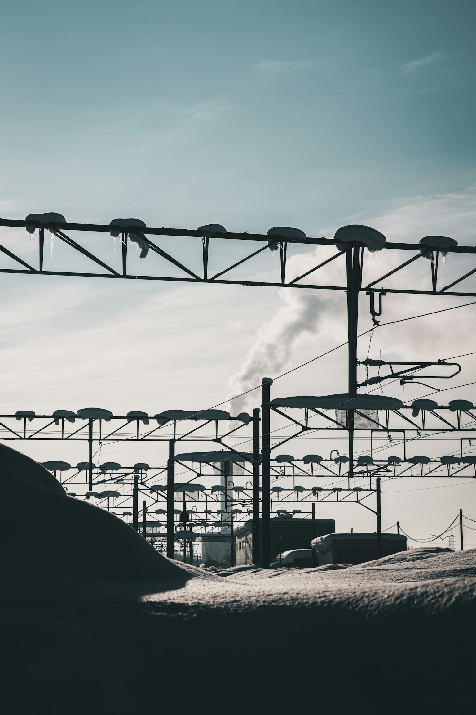 Paisaje industrial con humo de una chimenea y líneas de tren aéreas
