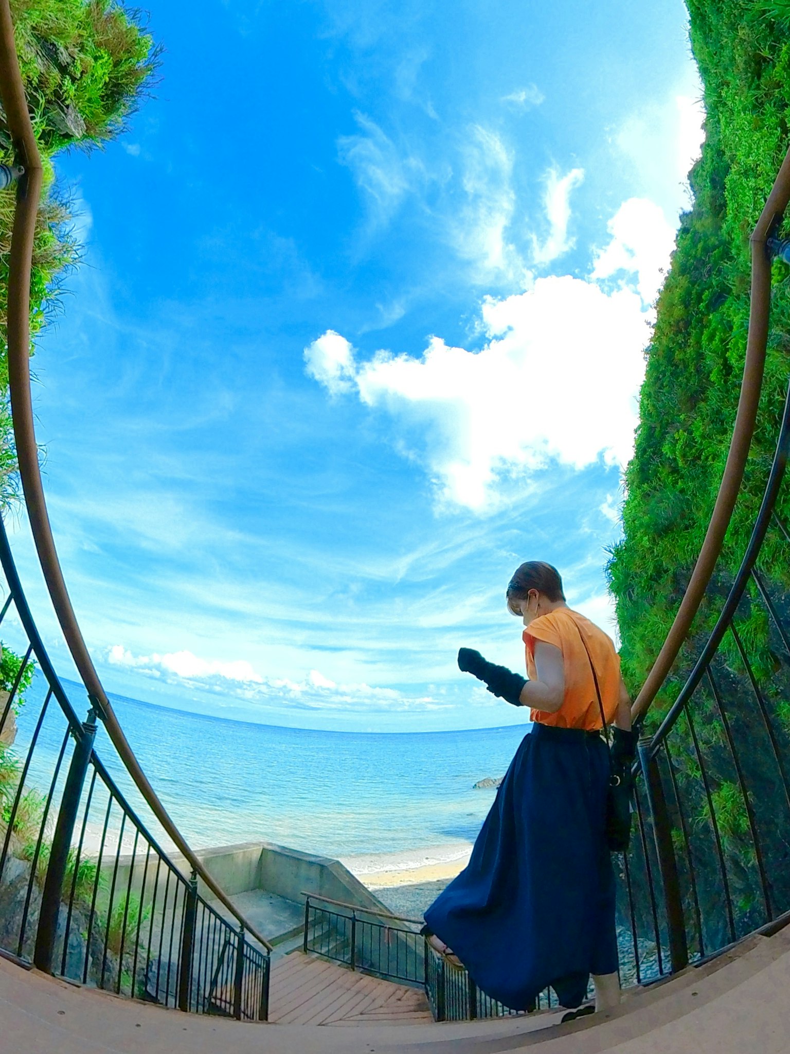 一個人在藍天和海洋背景下下樓梯的輪廓