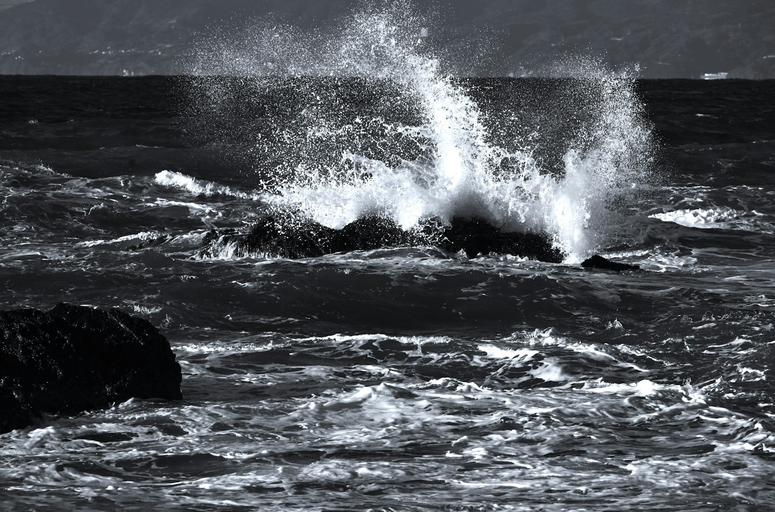 Olas del océano en blanco y negro rompiendo contra las rocas