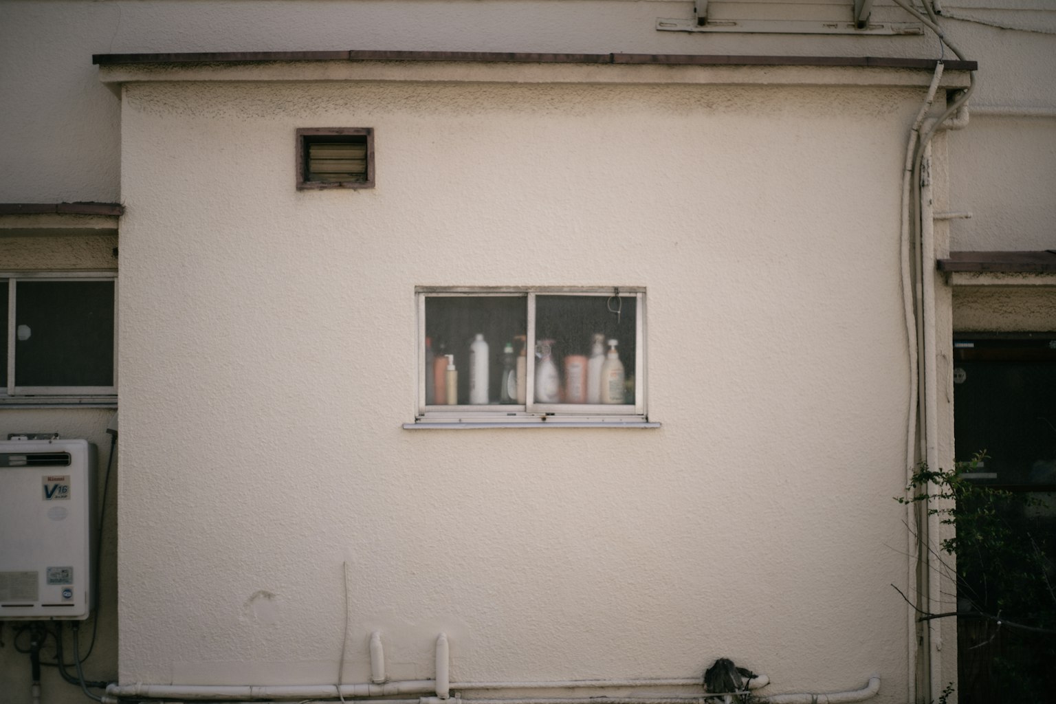 A small window on a white wall displaying several bottles