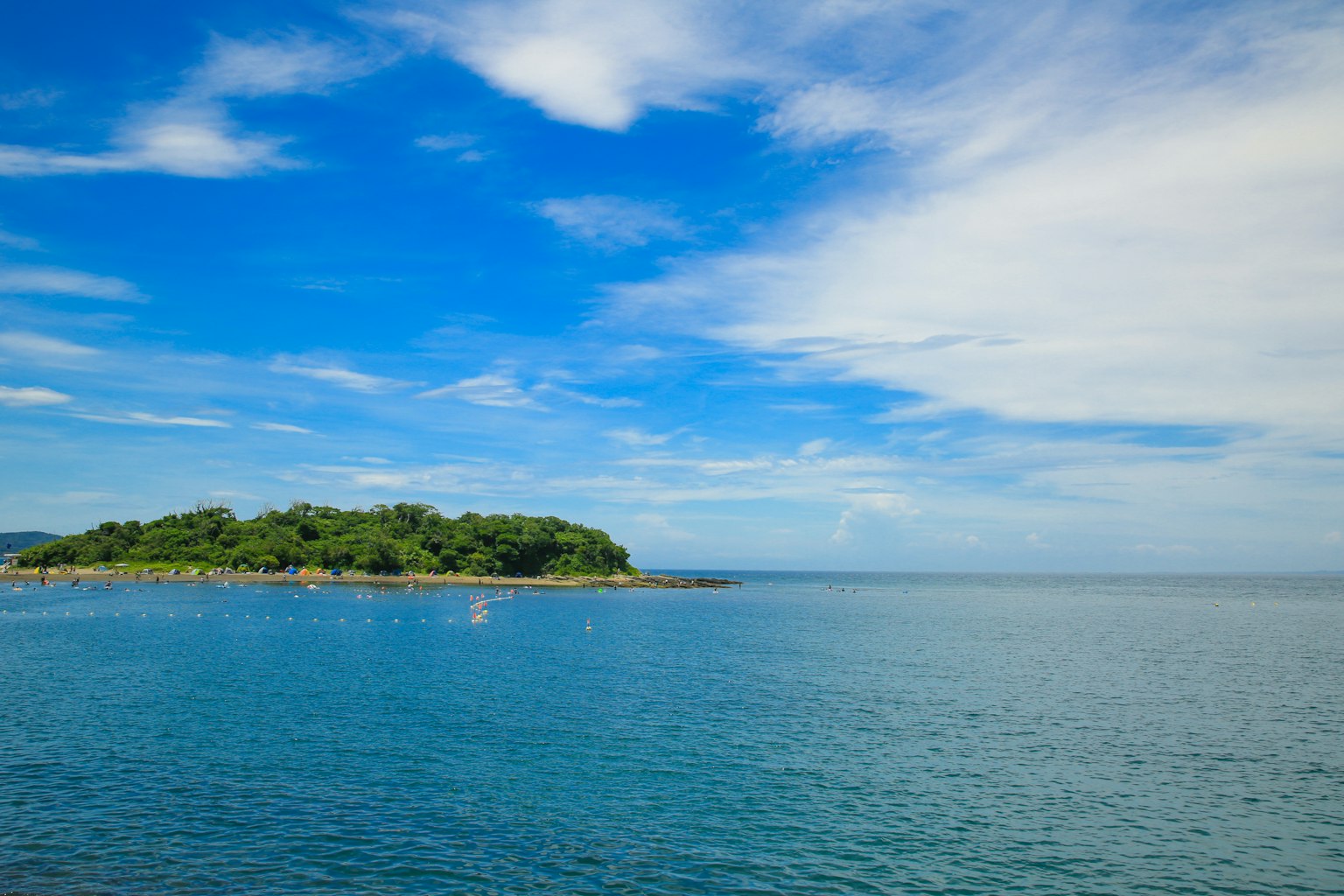 เกาะสีเขียวที่อยู่ท่ามกลางน้ำทะเลสีน้ำเงินสงบและท้องฟ้าสดใส