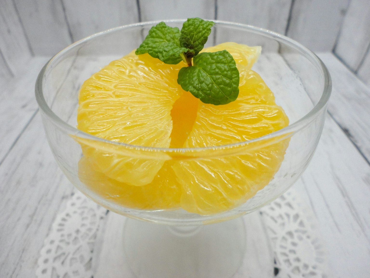Tranches de fruits orange servies dans un bol transparent avec des feuilles de menthe