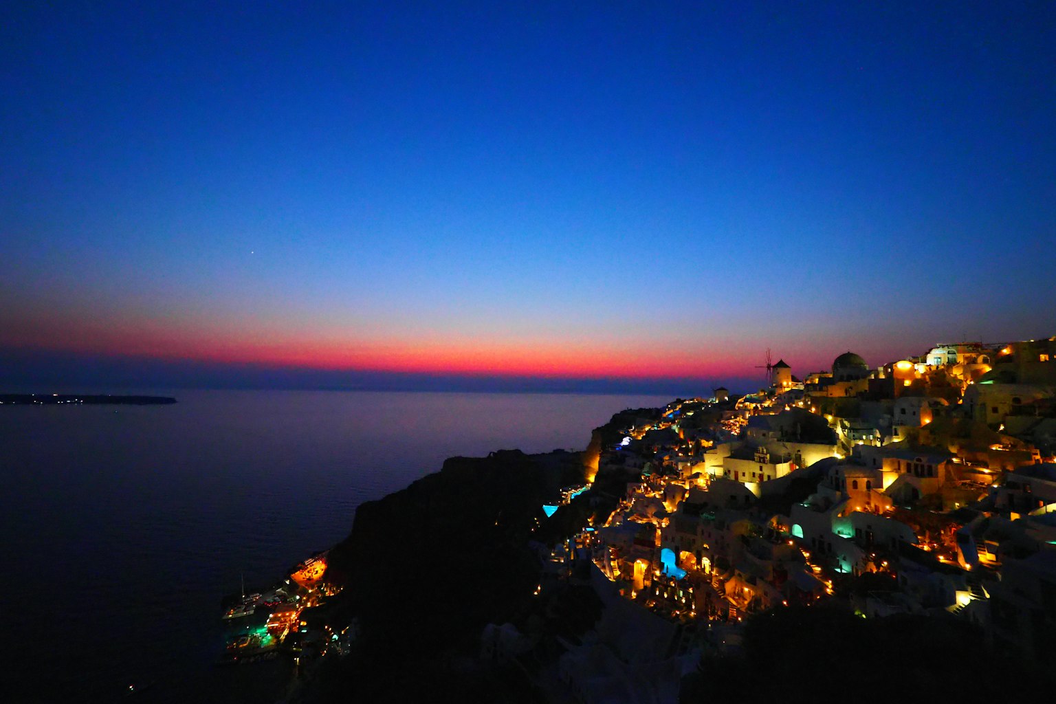 Bellissimo tramonto che si riflette sul mare luci della città che brillano