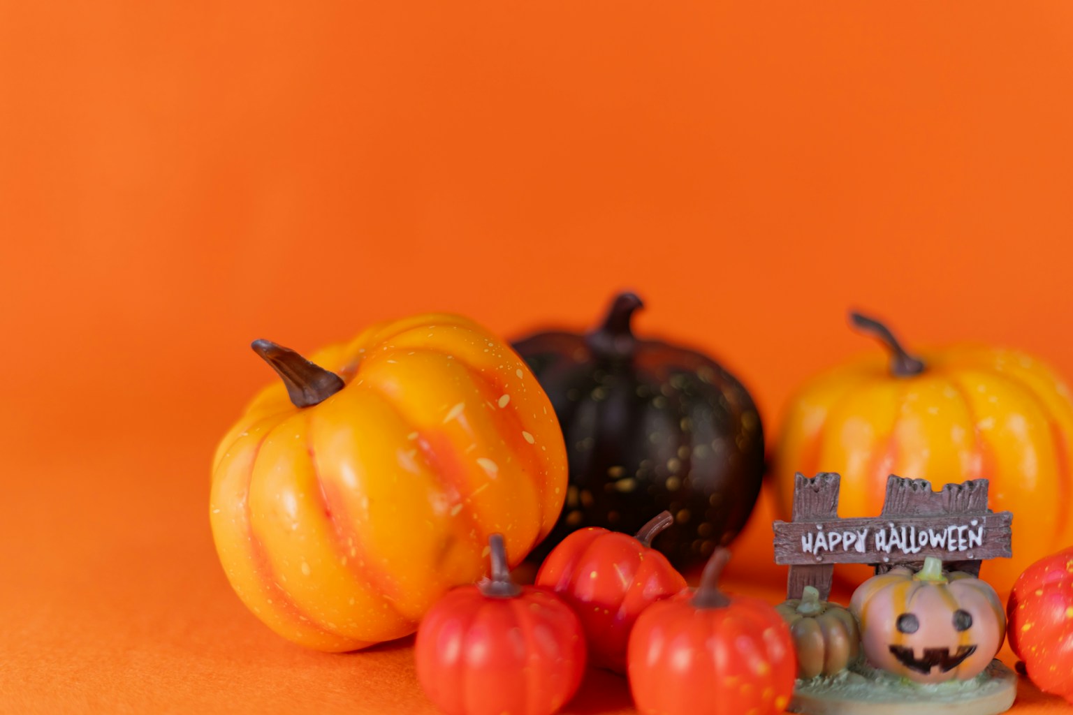 Koleksi labu berwarna-warni dengan dekorasi Halloween di latar belakang oranye