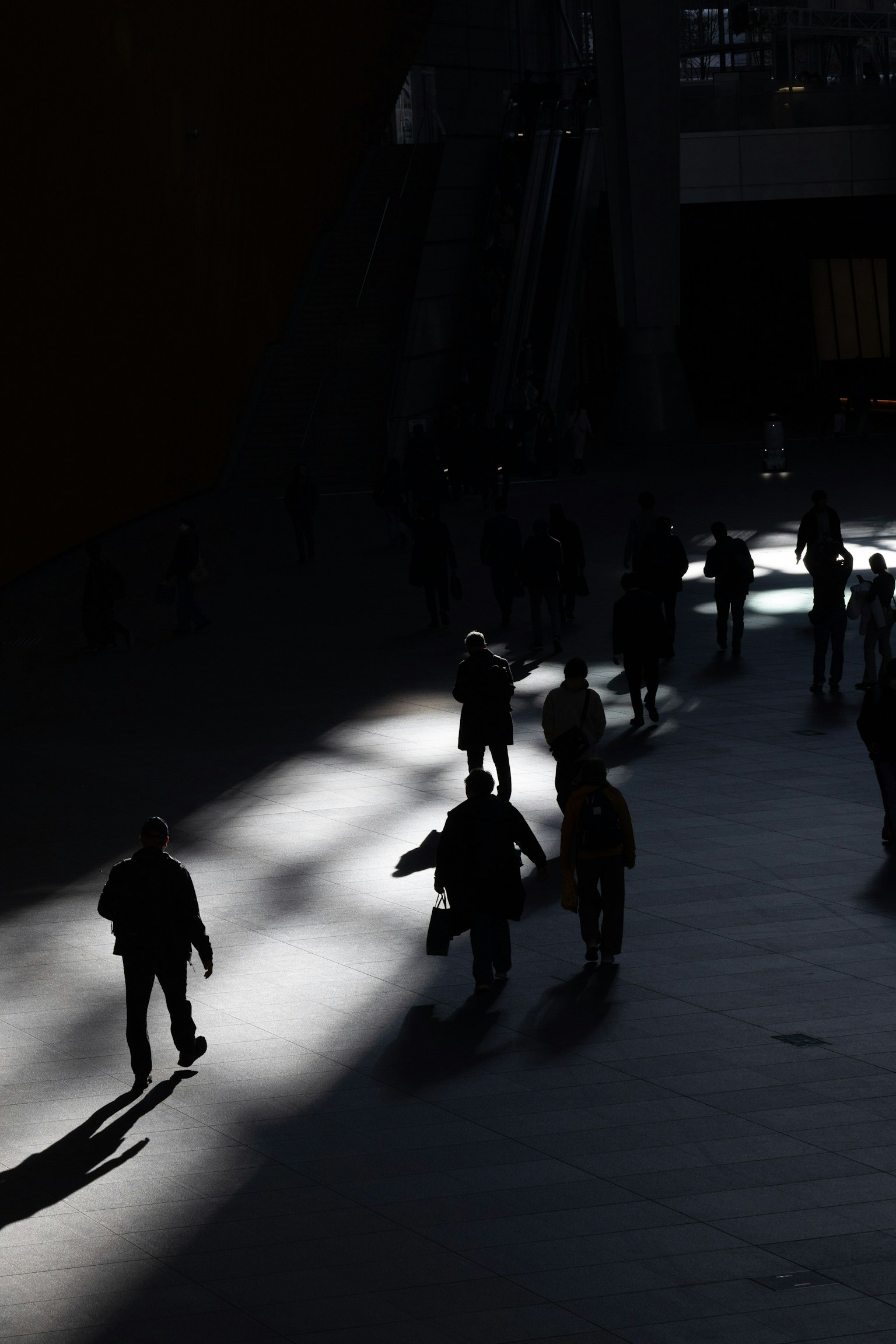 People walking in shadows with beams of light creating a dramatic atmosphere