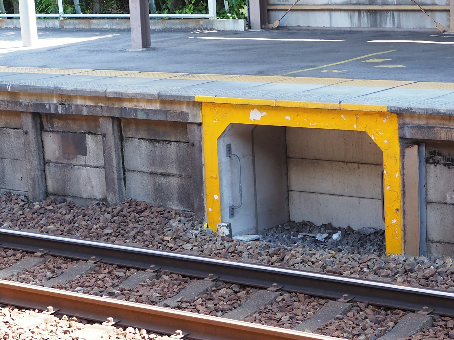 Estructura amarilla debajo de la plataforma del tren con vías visibles
