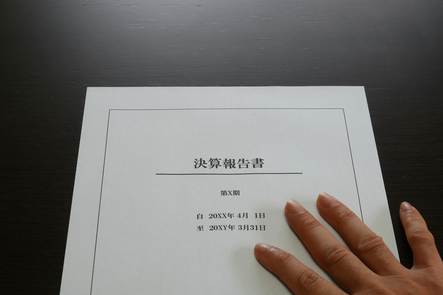 Una mano descansando sobre una cubierta de documento con texto en japonés