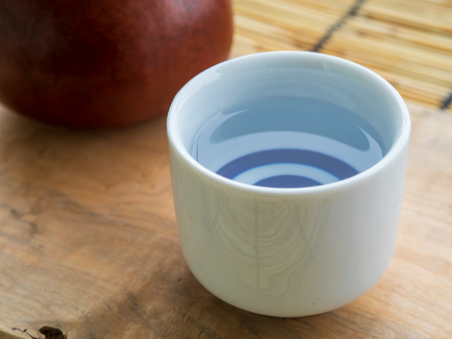 A white ceramic cup filled with water showing blue patterns at the bottom