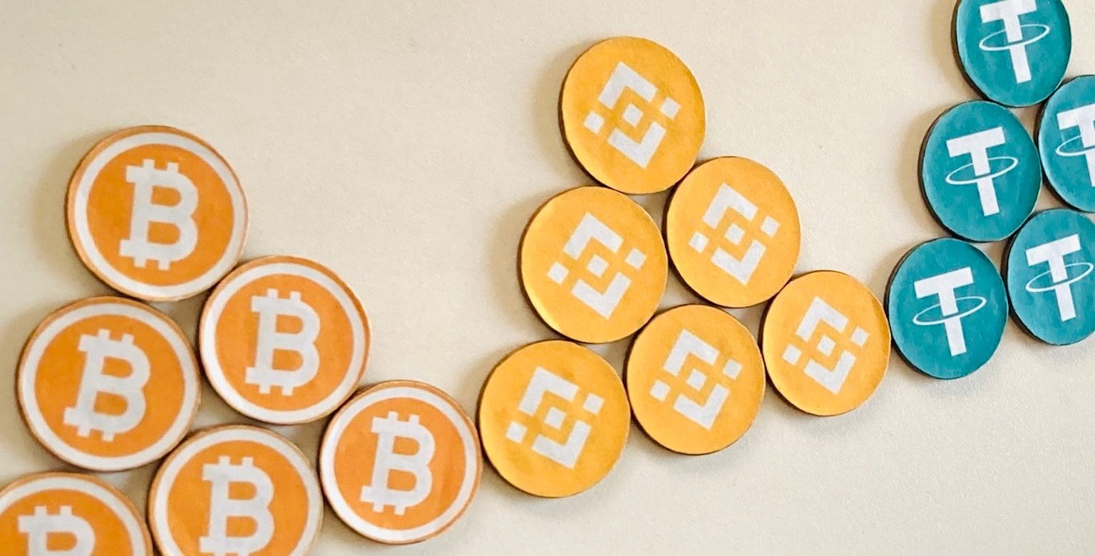 圖片展示了包括比特幣和泰達幣在內的多種顏色的加密貨幣硬幣
