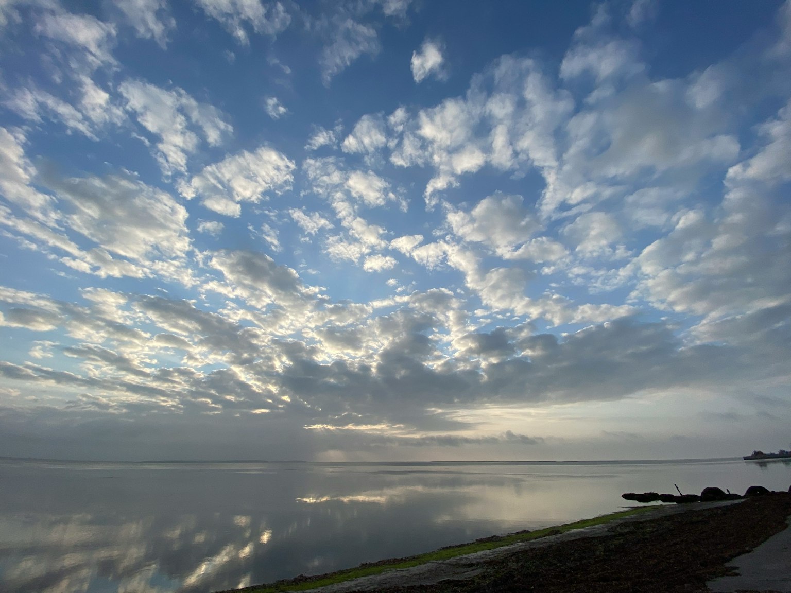 ทะเลสงบสะท้อนท้องฟ้าที่เต็มไปด้วยเมฆ