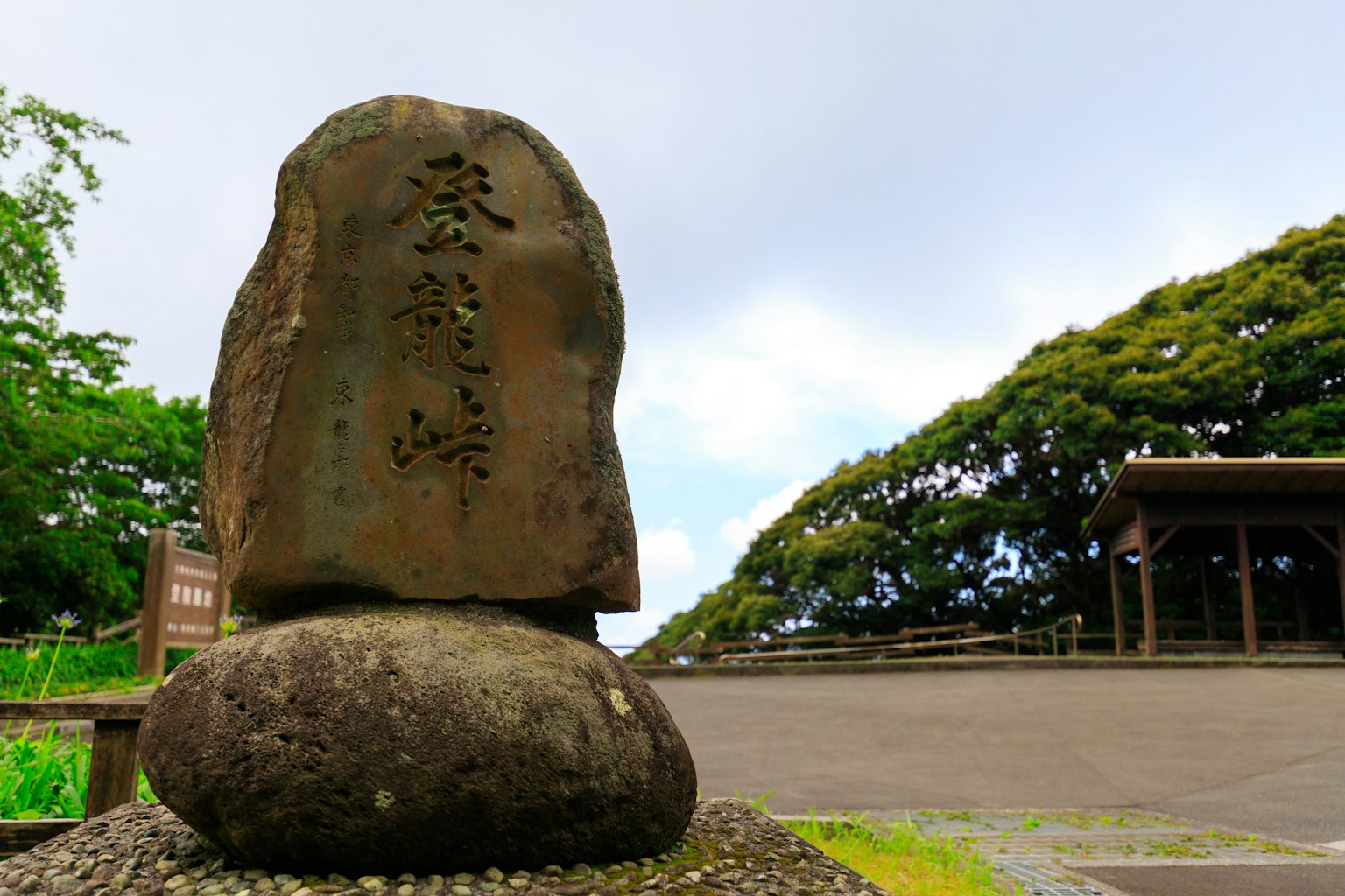 Large stone with engraved characters and surrounding green landscape