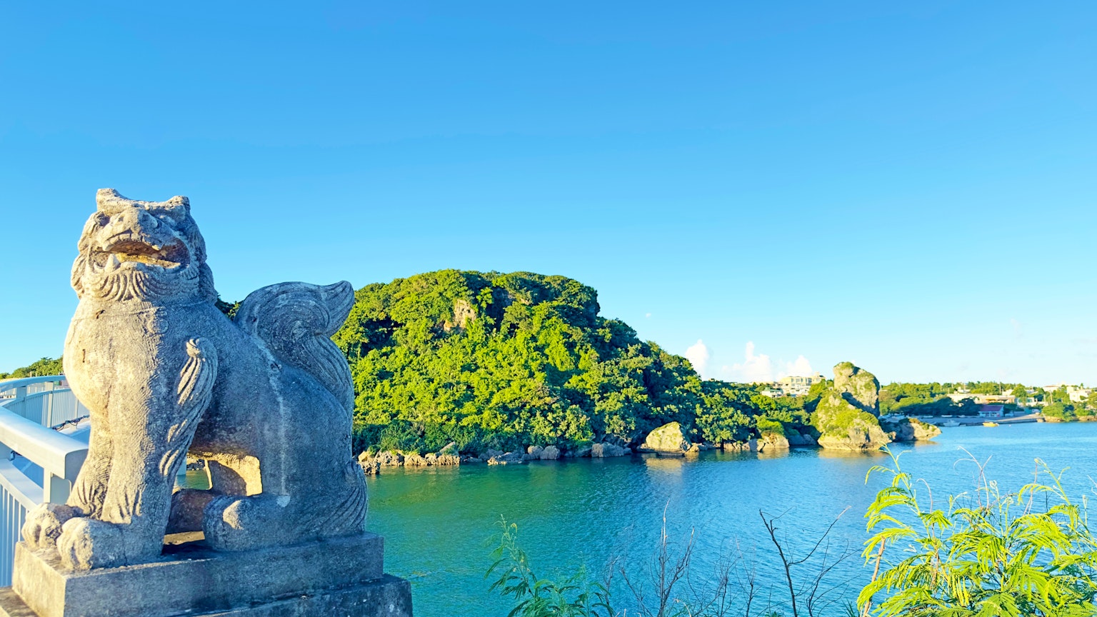 Steinlöwe, der einen ruhigen blauen See und eine grüne Insel überblickt
