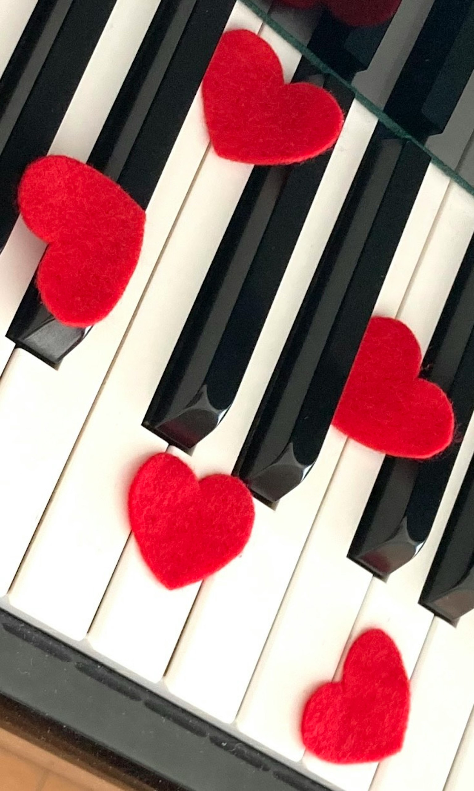 Teclas de piano decoradas con corazones rojos de fieltro