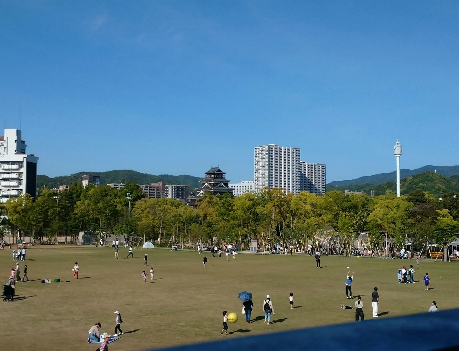 Scène de parc avec des gens jouant sous un ciel bleu et des arbres verts