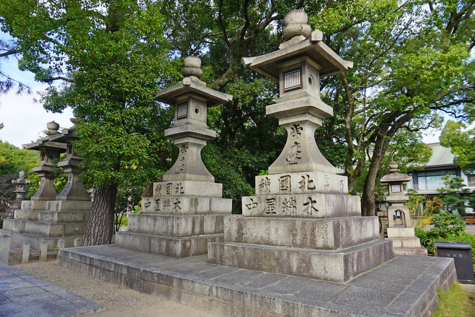 Traditionelle japanische Steinfackeln in einem ruhigen Garten, umgeben von üppigen Bäumen