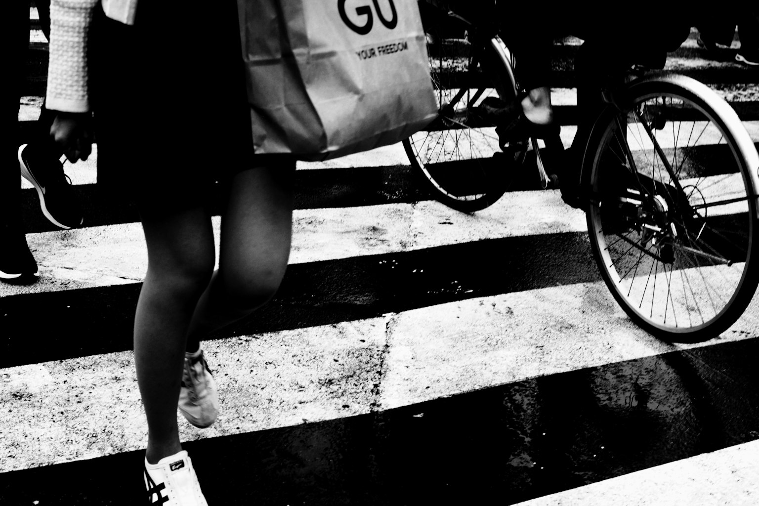 Una persona che attraversa un attraversamento pedonale con una bicicletta nelle vicinanze che porta una borsa della spesa