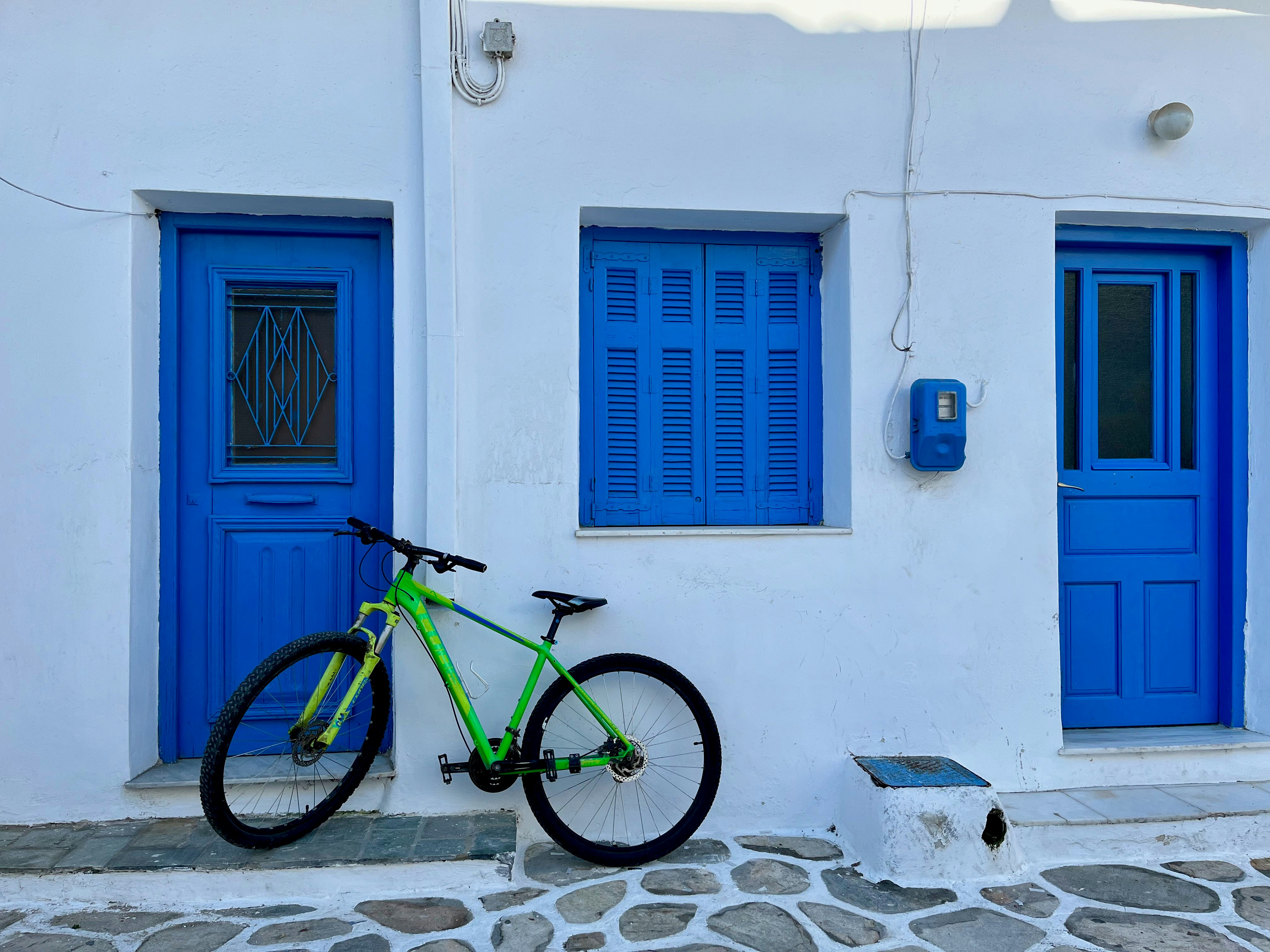 bicycle parked in a white-walled alley with blue doors