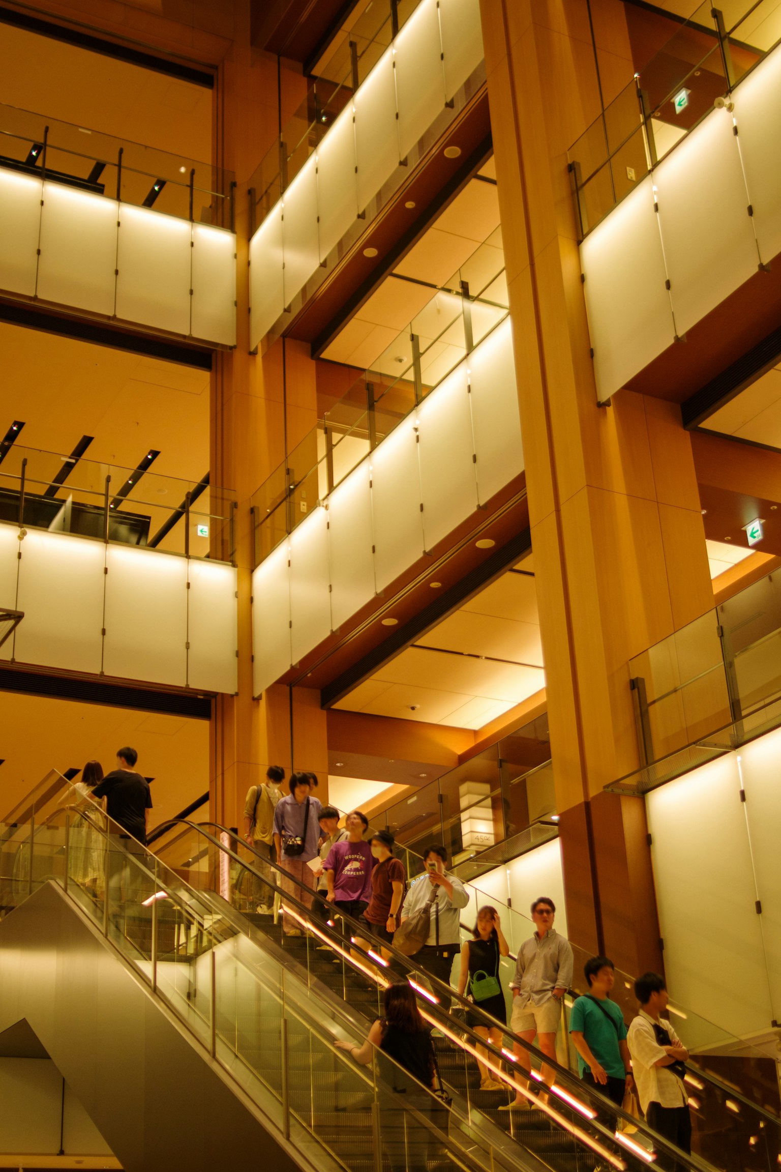 People descending a staircase in a modern building featuring bright lighting and wooden design elements