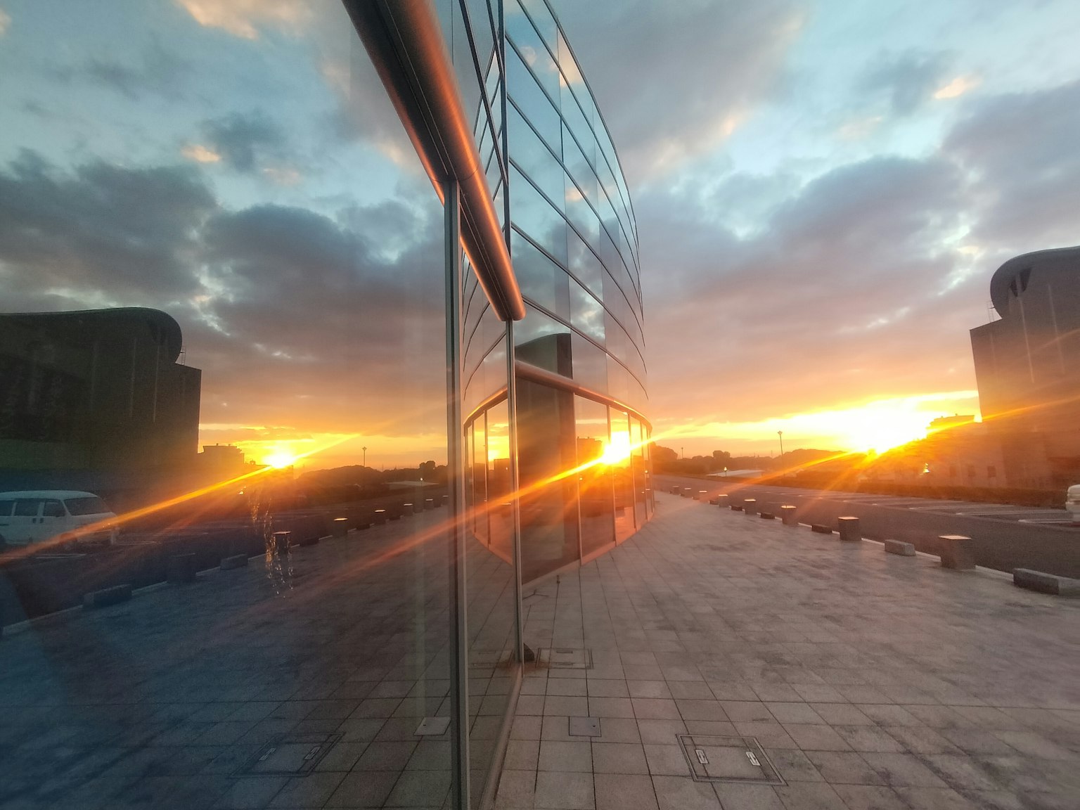 Sonnenuntergangsreflexion auf einem Glasgebäude mit gepflastertem Gehweg