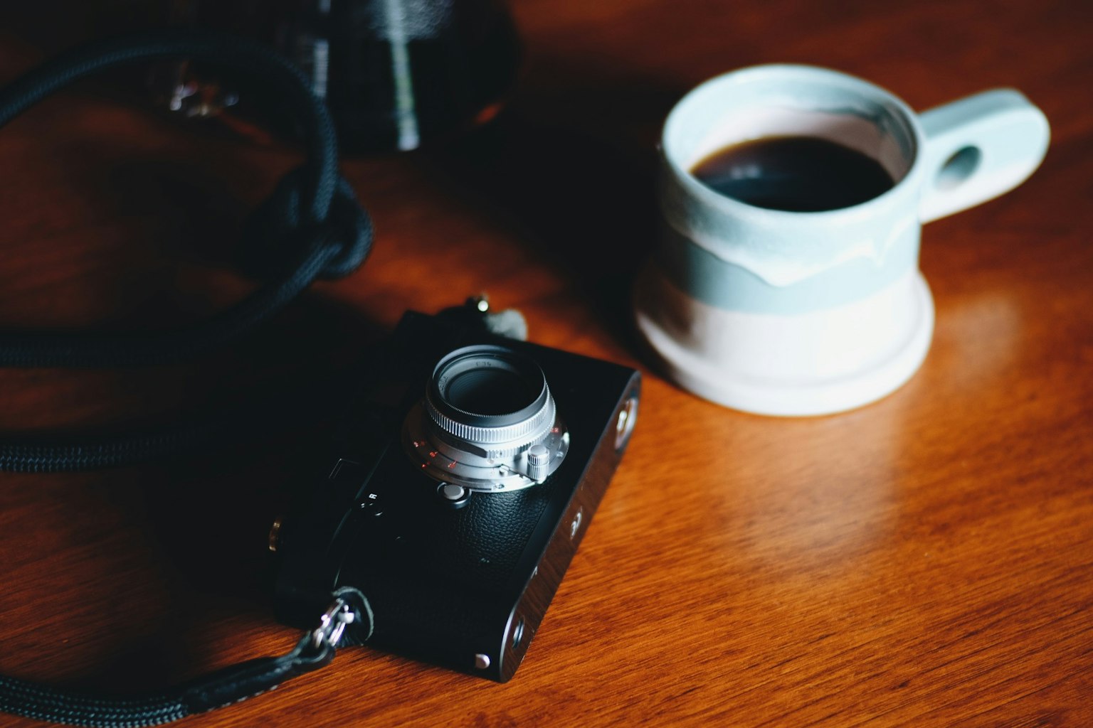Un appareil photo et une tasse de café posés sur une table en bois