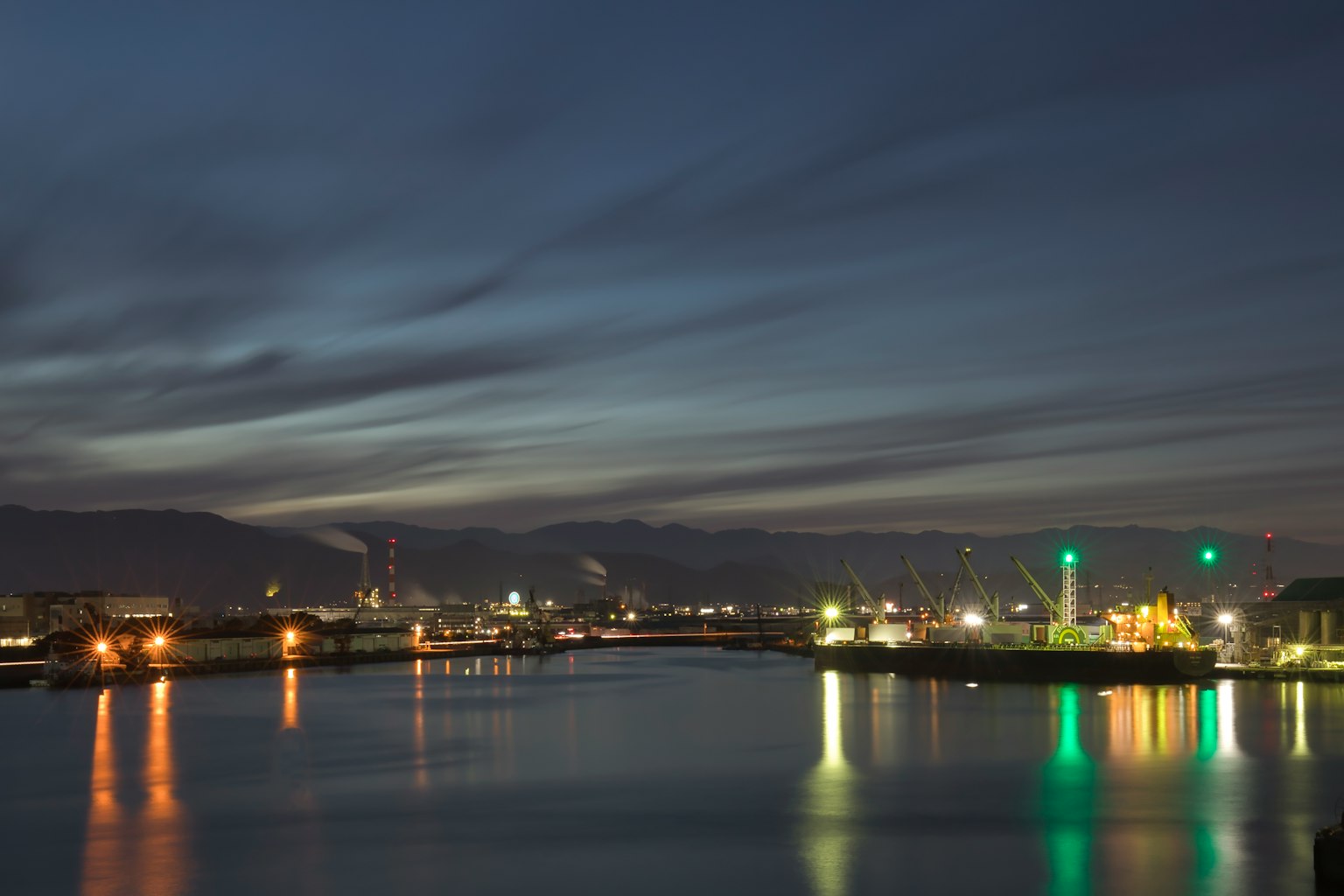 Night view of a river and industrial area with reflections of lights