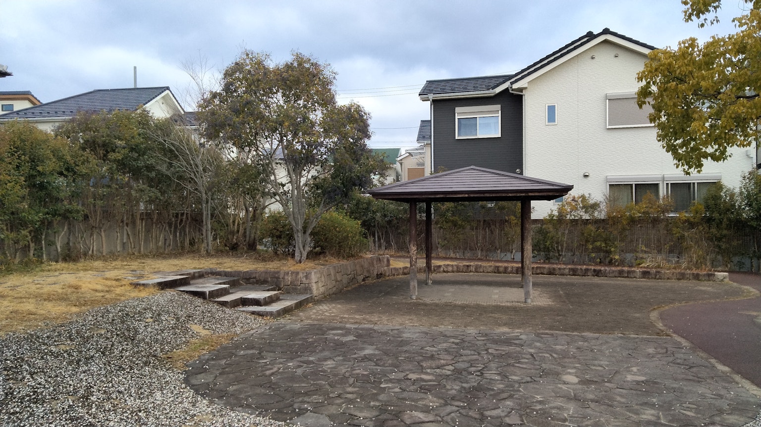 Park pavilion with surrounding trees and gravel path