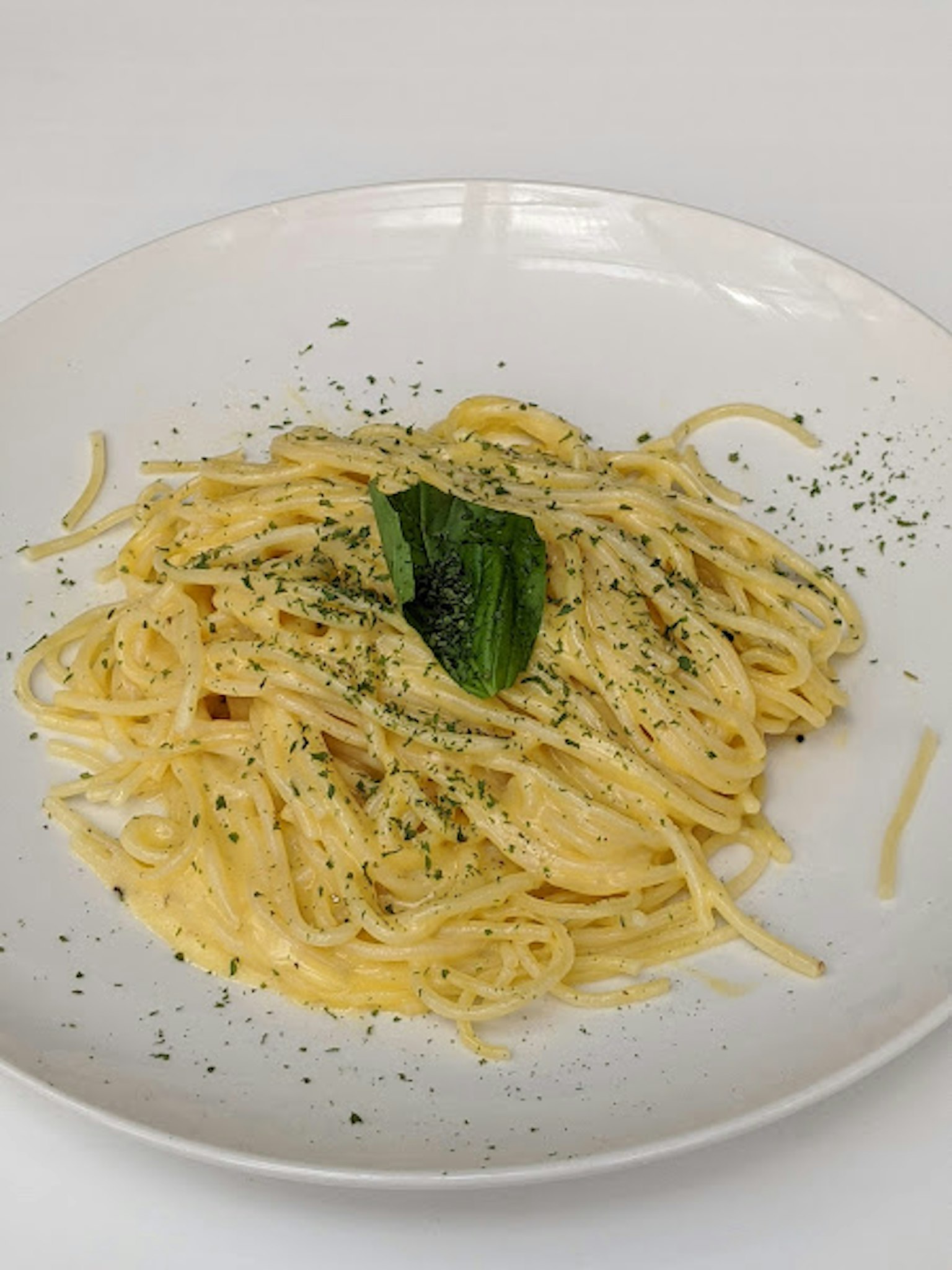 Cremige Pasta auf einem Teller mit Basilikumblättern serviert