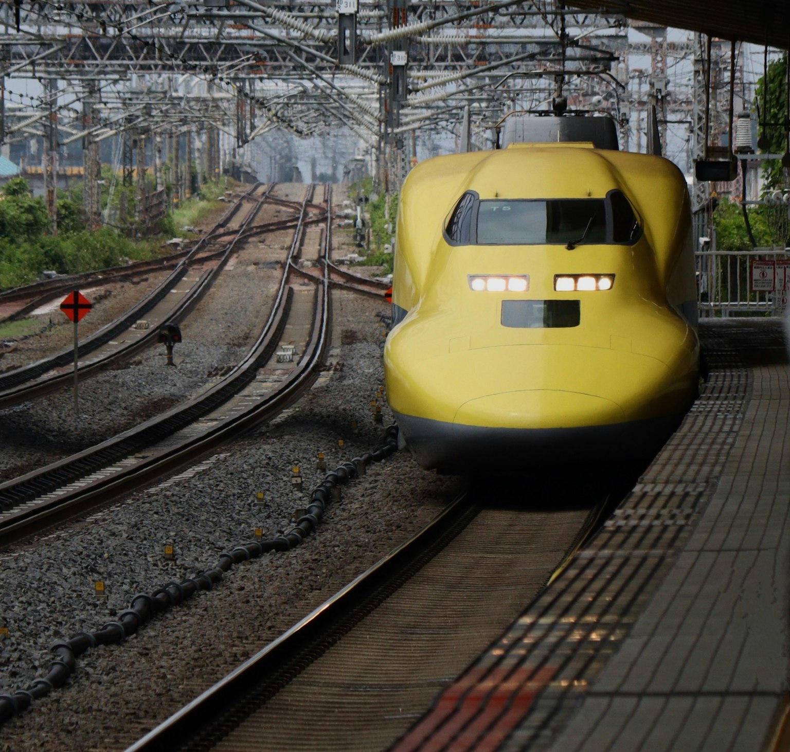 Yellow Shinkansen train approaching a station in Japan