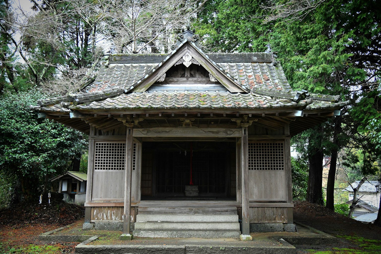 Traditional wooden shrine building surrounded by greenery in a tranquil setting