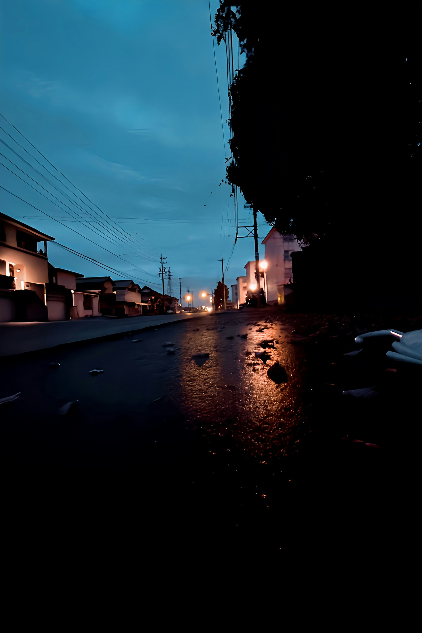 雨上がりの路地で濡れた道路と街灯の光が広がる風景