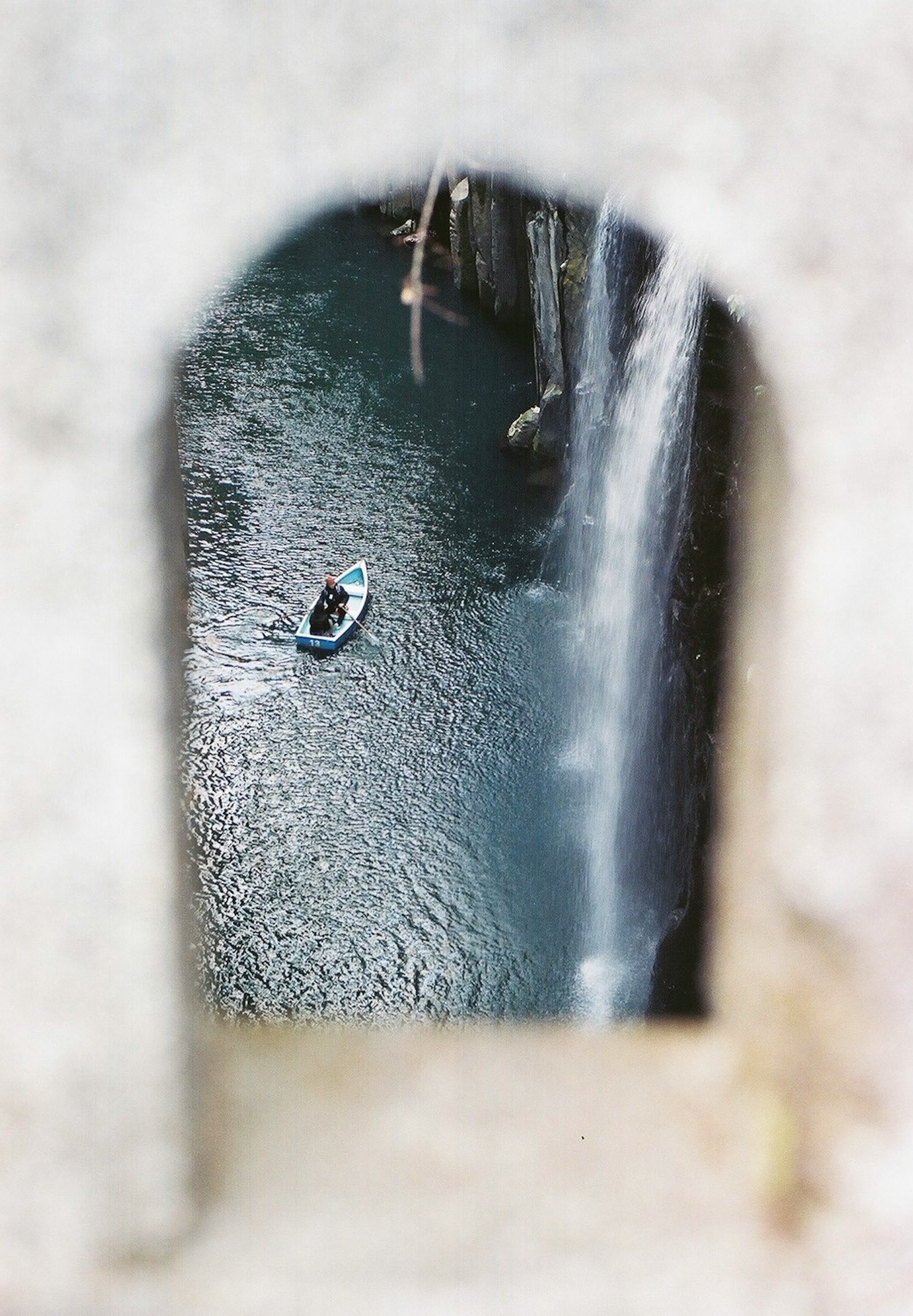 Una persona in una piccola barca su un fiume dietro una cascata