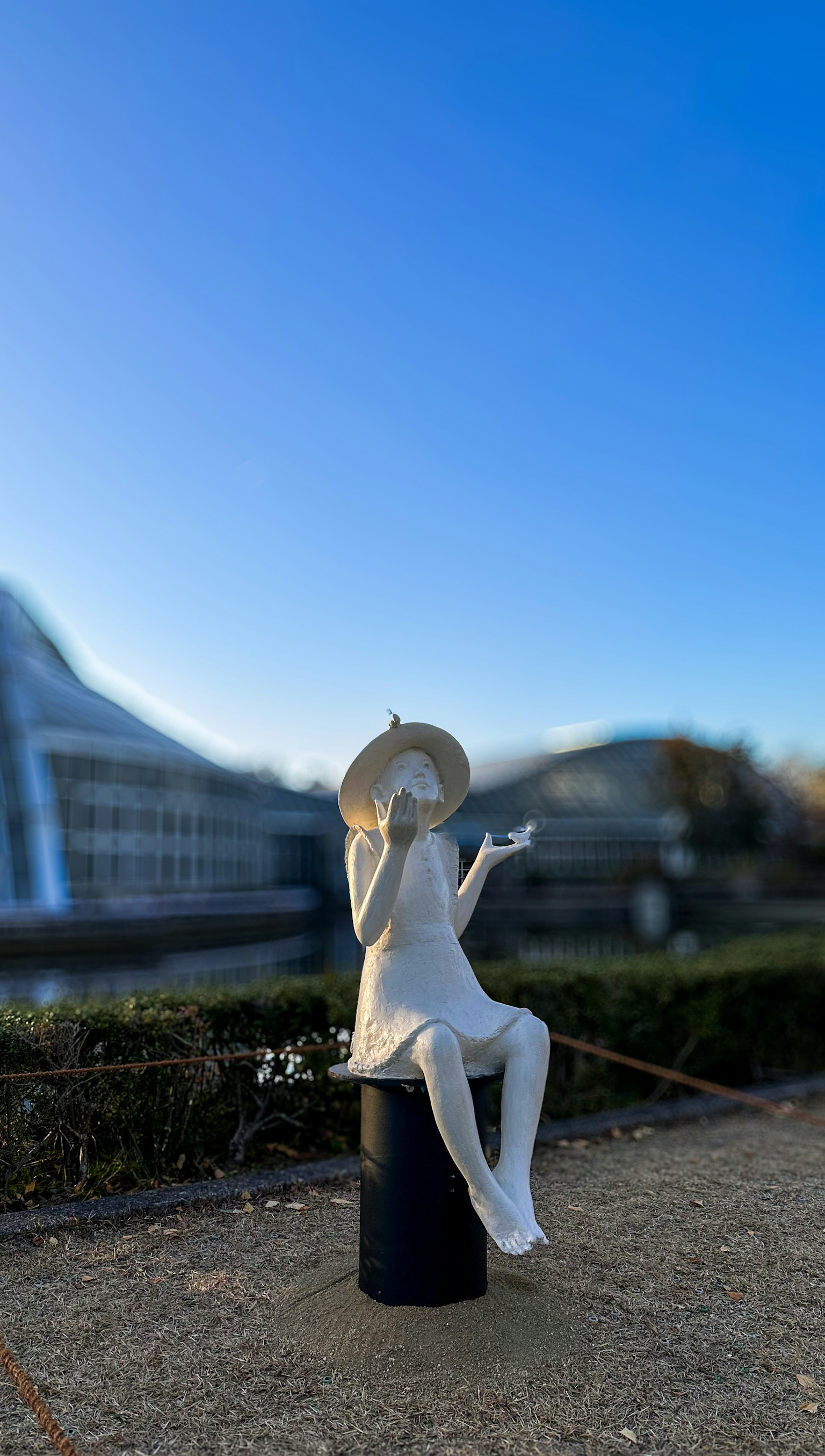 Scultura bianca con cappello seduta pacificamente all'aperto