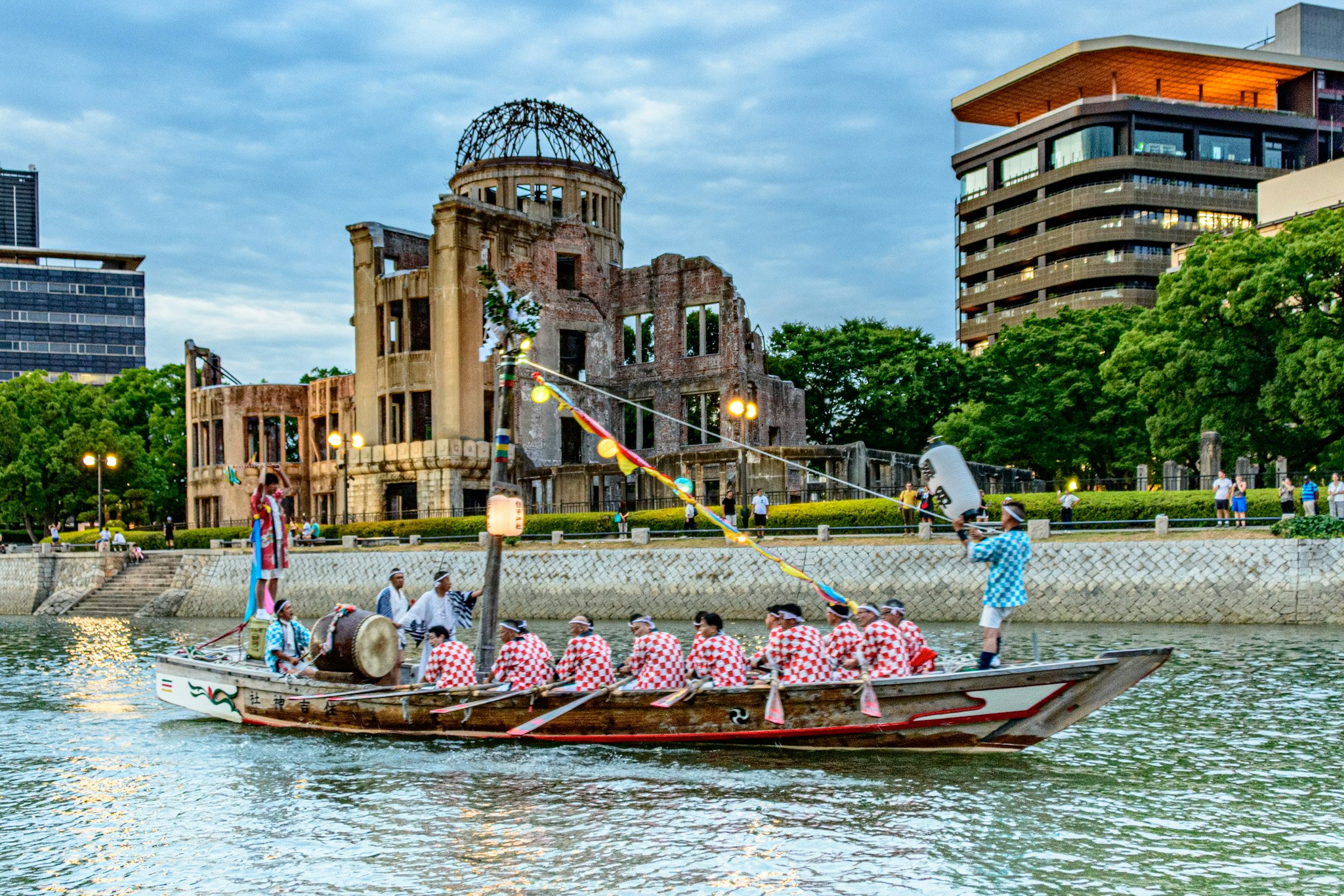 bambini su una barca rosa lungo un fiume con la Cúpola della bomba atomica