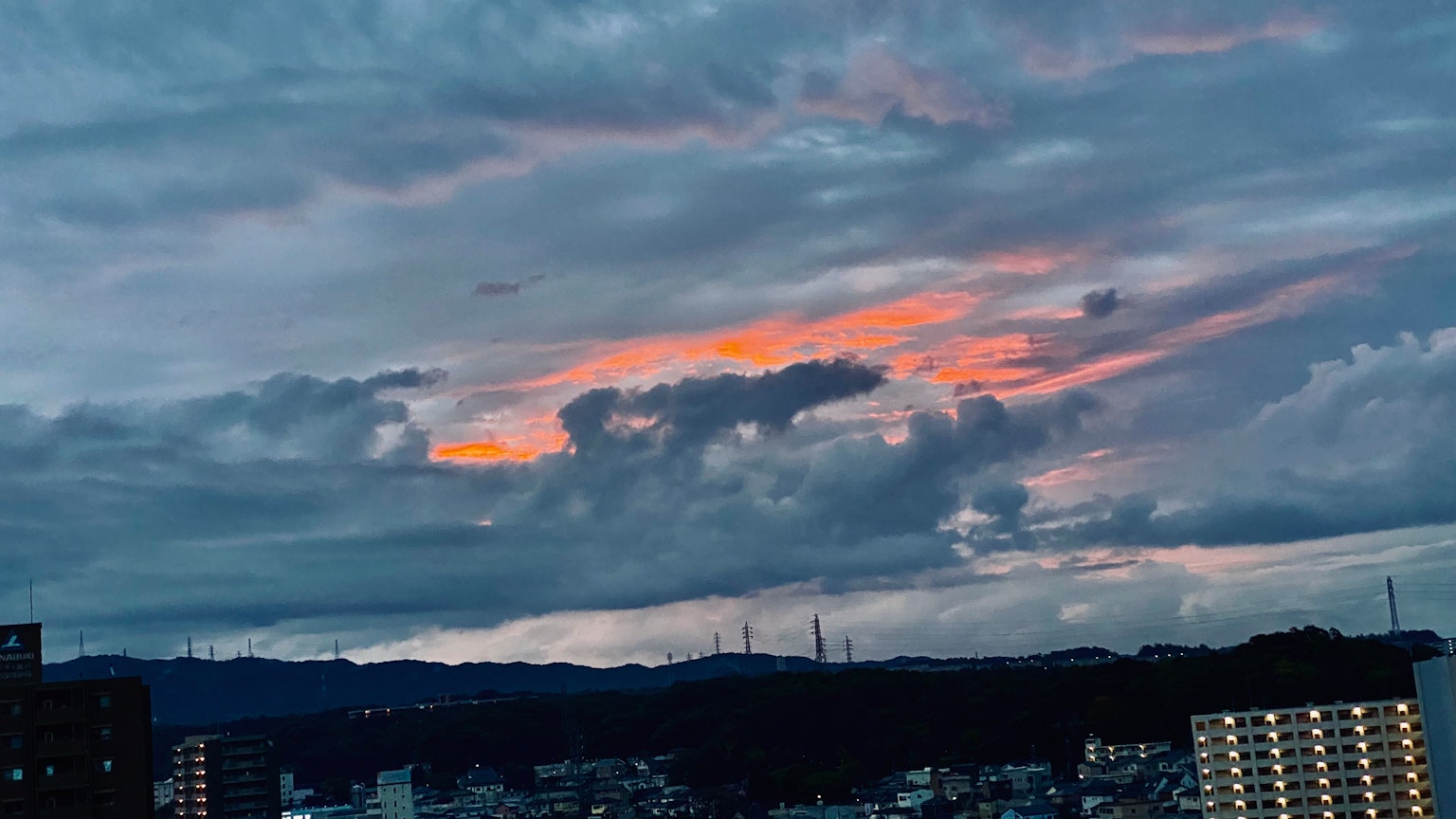 Ein lebendiger Sonnenuntergang mit orangefarbenen Wolken über der Stadtsilhouette