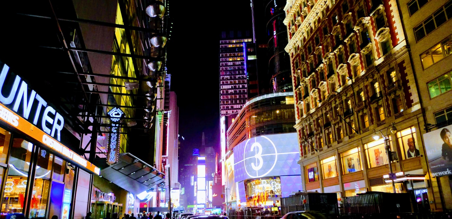 Escena nocturna vibrante de Times Square con luces de neón brillantes y tiendas