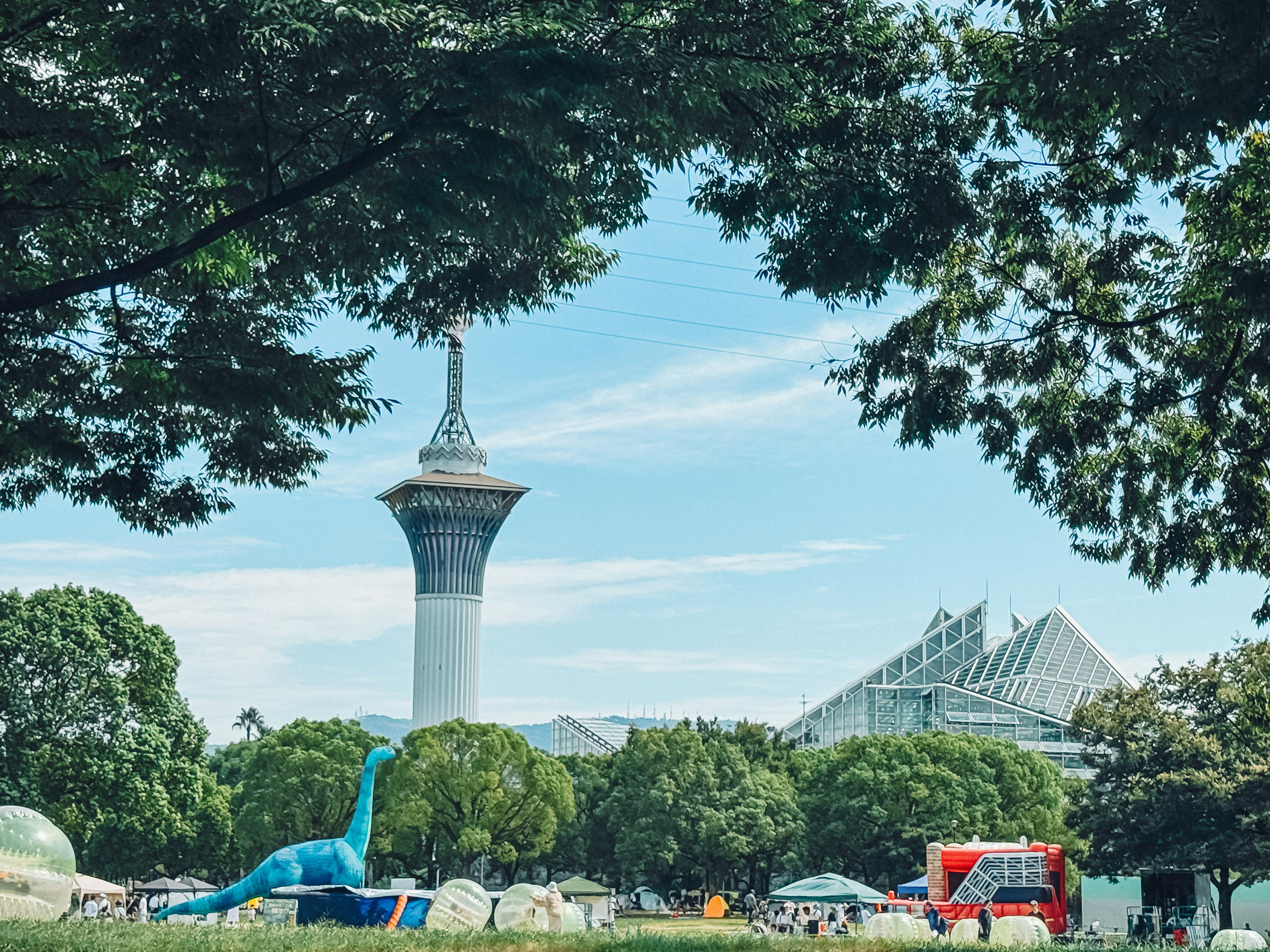 View of a tower and dome through trees in Tsurumi Ryokuchi Park