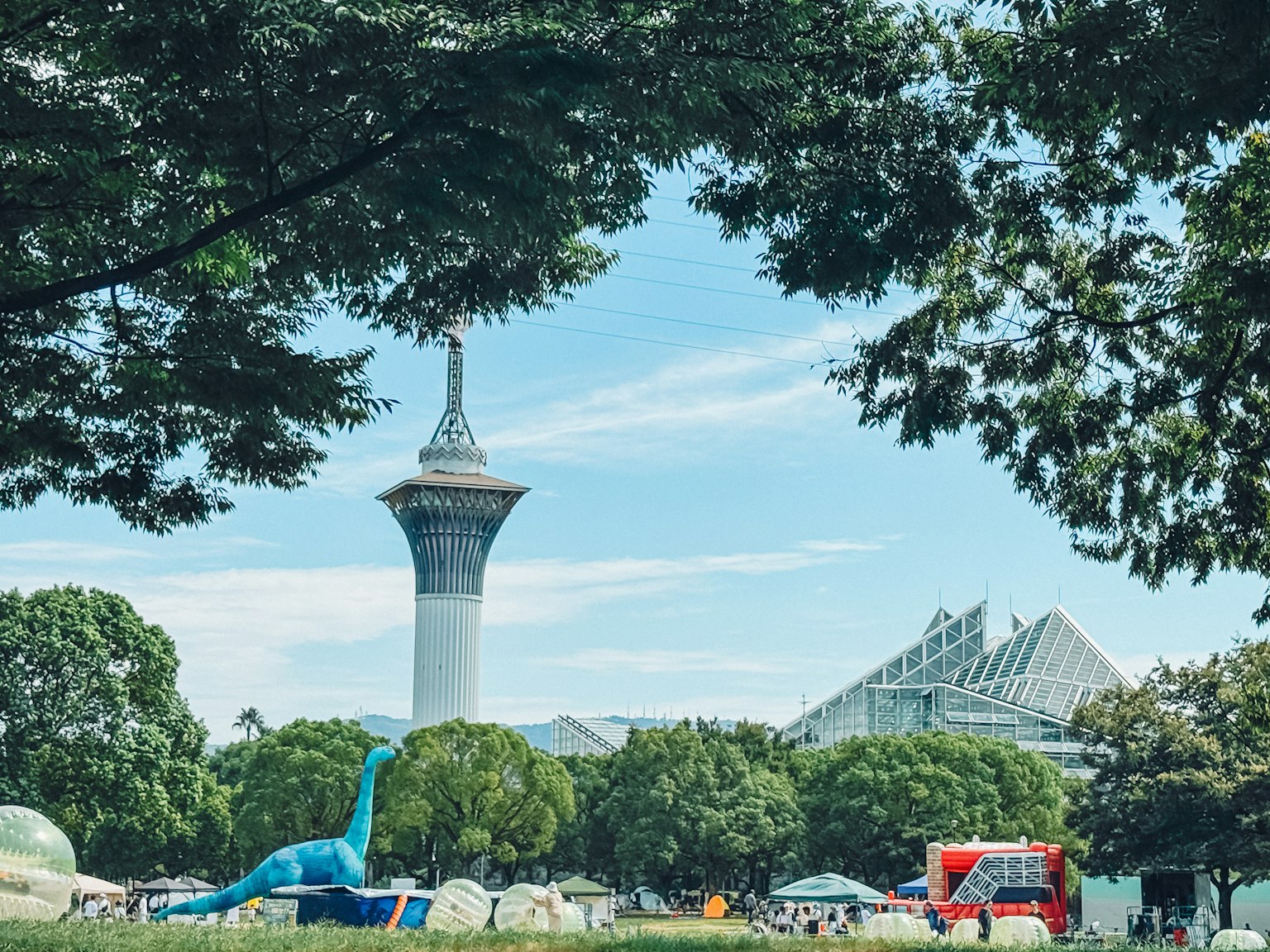 緑豊かな公園の中にあるタワーと恐竜のオブジェ