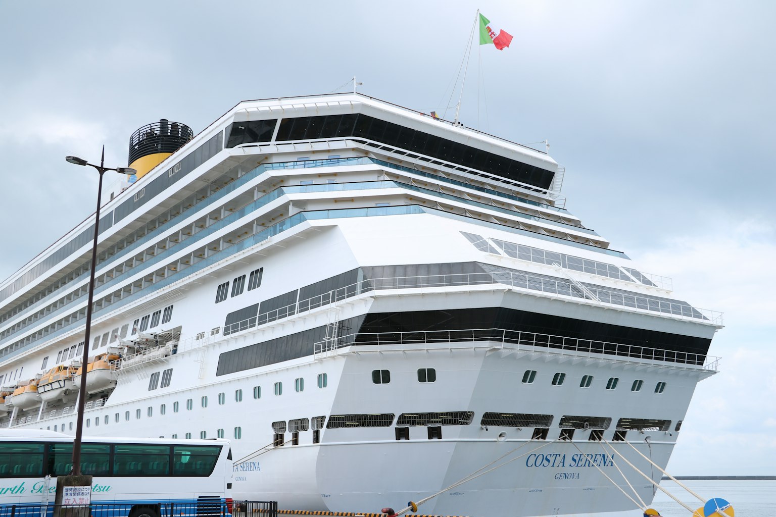 Large cruise ship docked at port with Italian flag