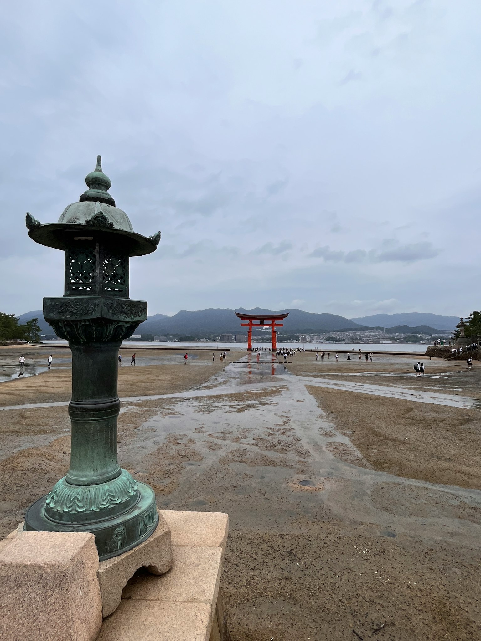 Scenic view of a lantern and a torii gate by the shore