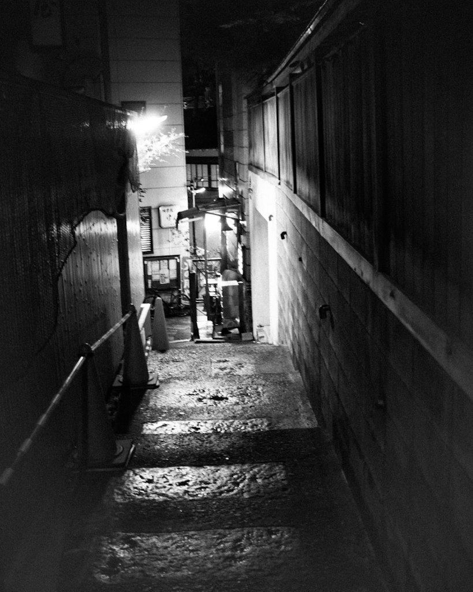 Vista de escaleras a lo largo de un callejón oscuro iluminado por luces