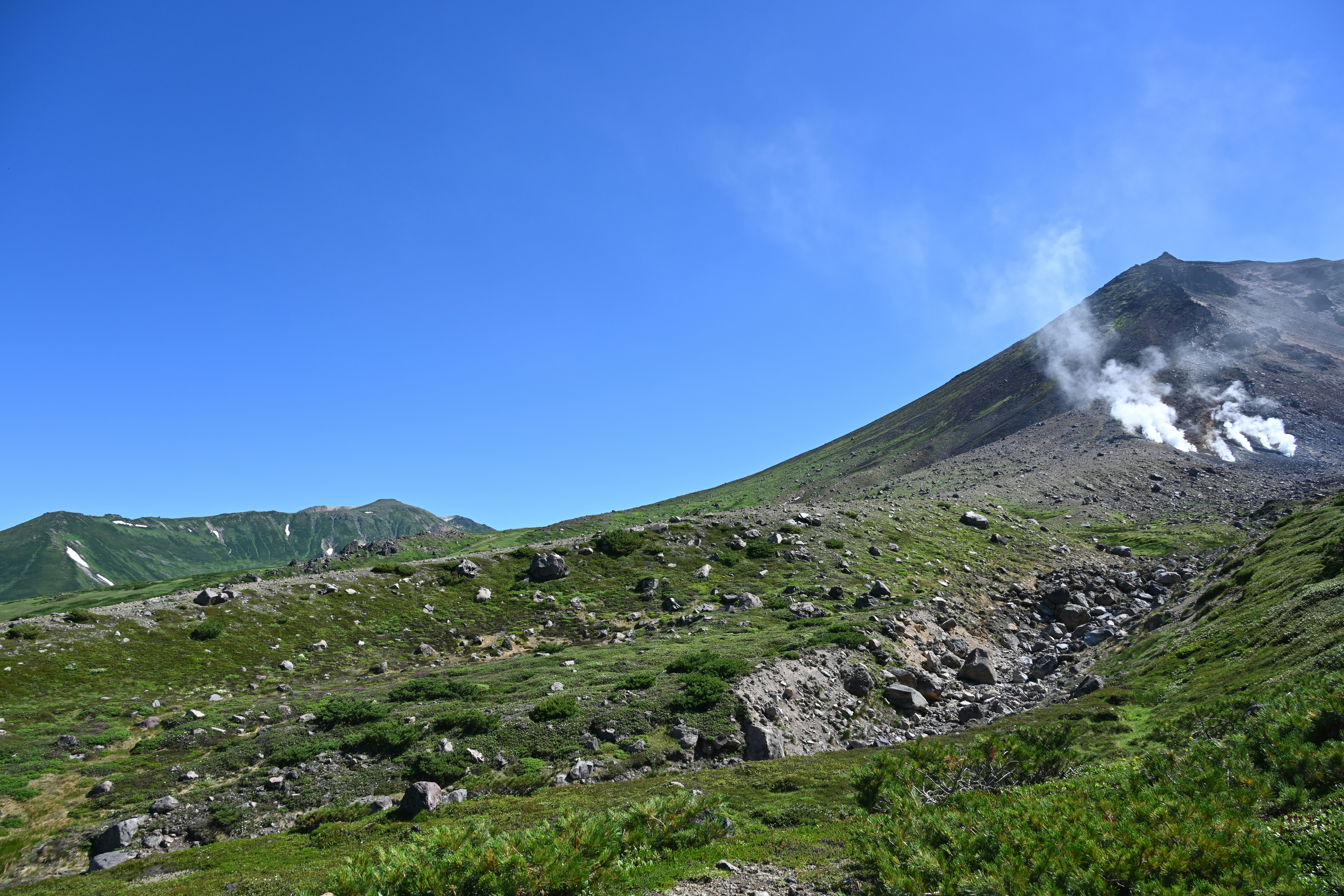 火山冒烟的景象与绿色高山草甸