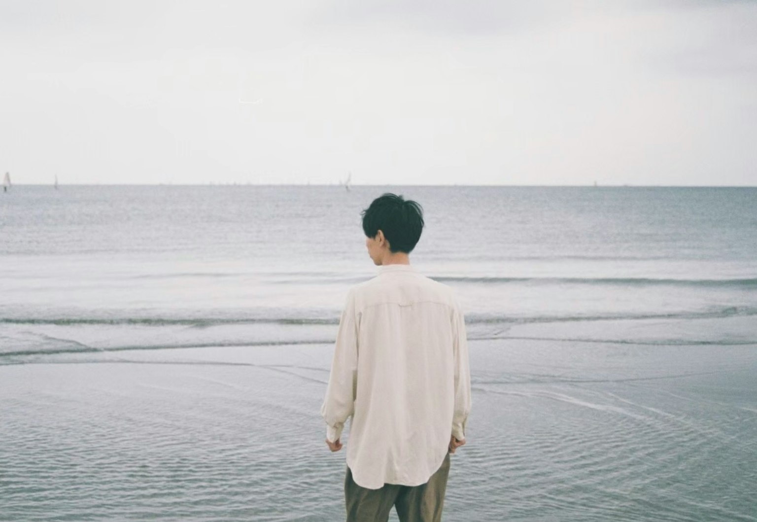 海邊站著的男人 陰雲密布的天空和寧靜的海面