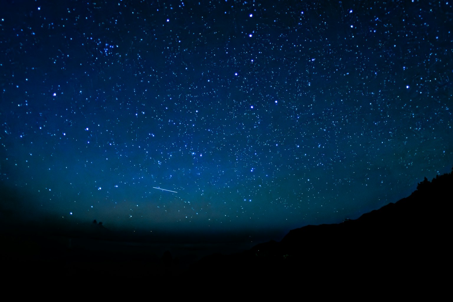 Amplio cielo nocturno lleno de innumerables estrellas y un horizonte oscuro