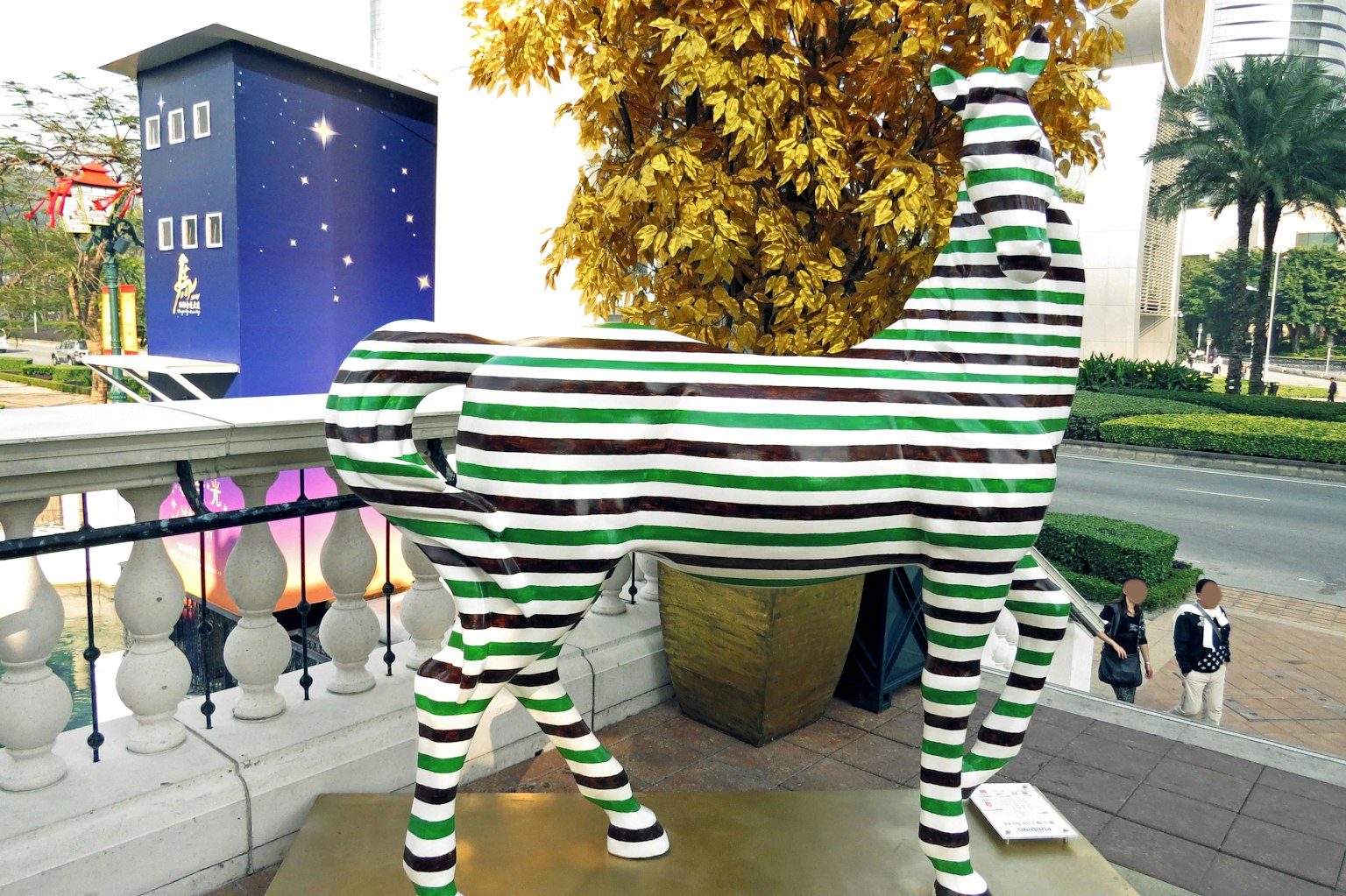 A green and white striped dog sculpture standing outdoors